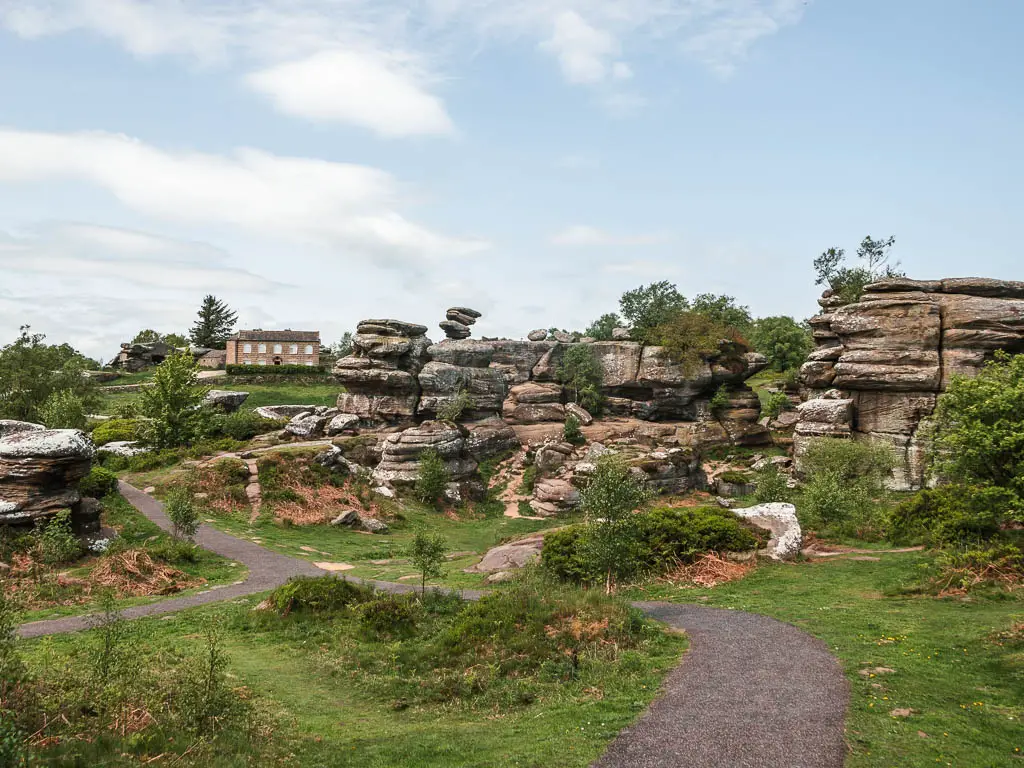 Looking across the green with a path running across it, and a mass of Brimham rocks on the other side, partway through the walk from Pateley Bridge.