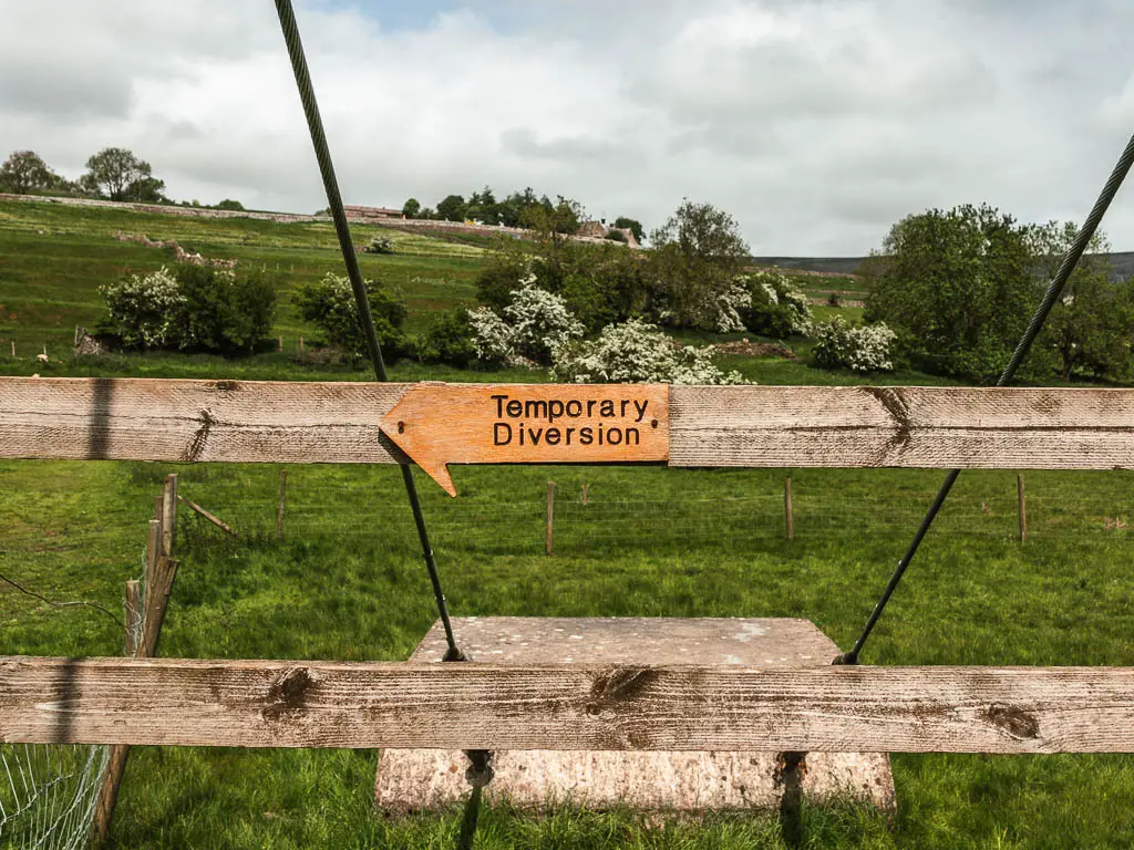 A wooden arrow sign pointing left for a temporary diversion, on the walk back to Reeth from the suspension bridge. 