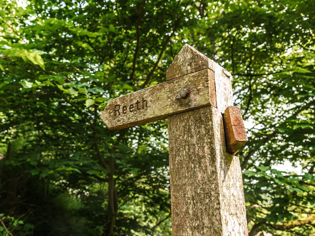 A wooden trail signpost pointing the way to walk to Reeth.