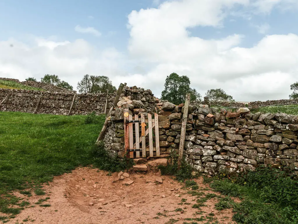 A wooden gate in the rugged stone wall.