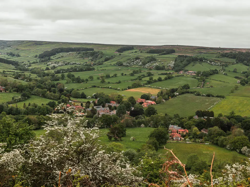 Looking down over the white cherry blossom trees to the village of Rosedale Abbey below, near the end of the walk. Rosedale Abbey is sitting at the bottom of the valley, and is surrounded by trees.