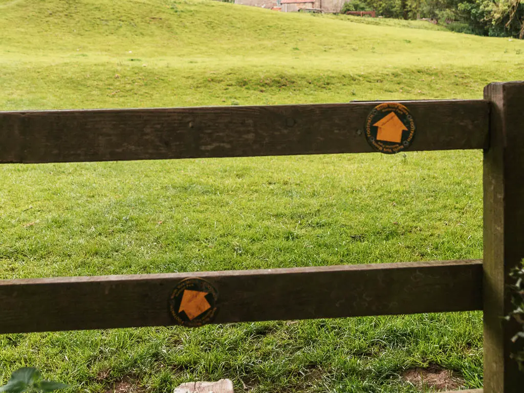 Two yellow arrows on the wooden fence, pointing left and ahead to the right.