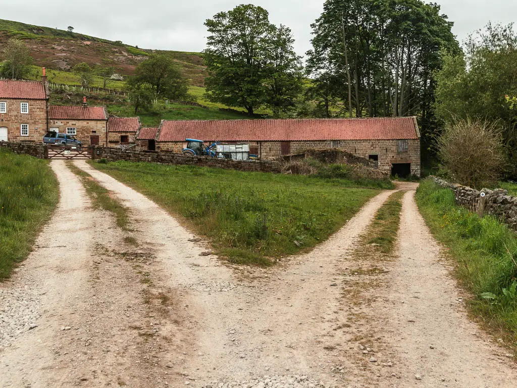 A fork in the gravel path, with farm buildings straight ahead.