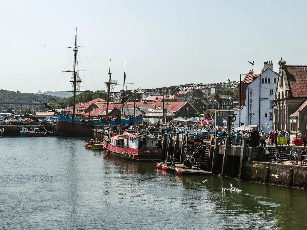 Looking along the river Esk, with a ship and fishing boats along the side ahead. 