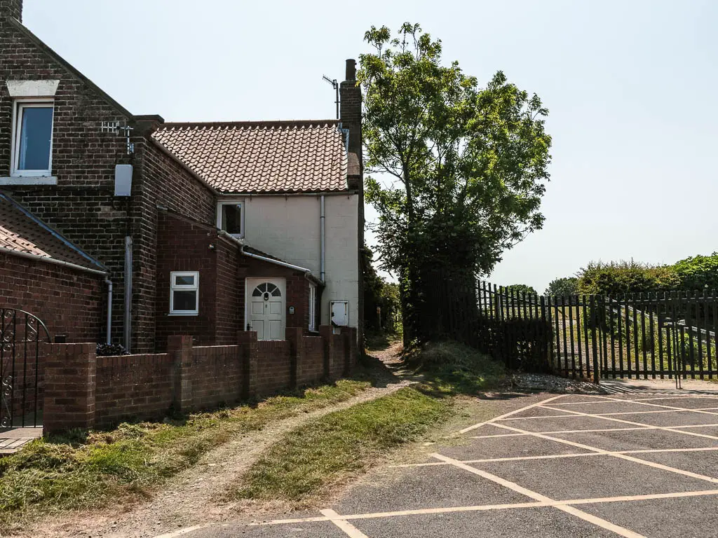 A yellow marked road box on the right, and houses to the left, with a public footpath between the two.