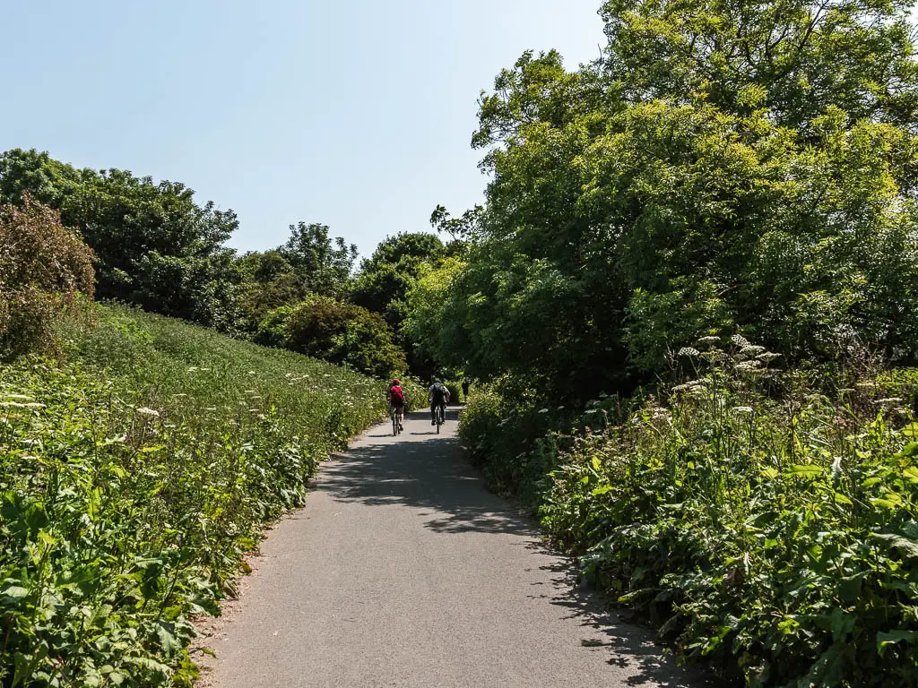 The Cinder track, lined with bushes and trees, and a couple of cyclists ahead, on the walk back to Robin Hood's Bay from Whitby.