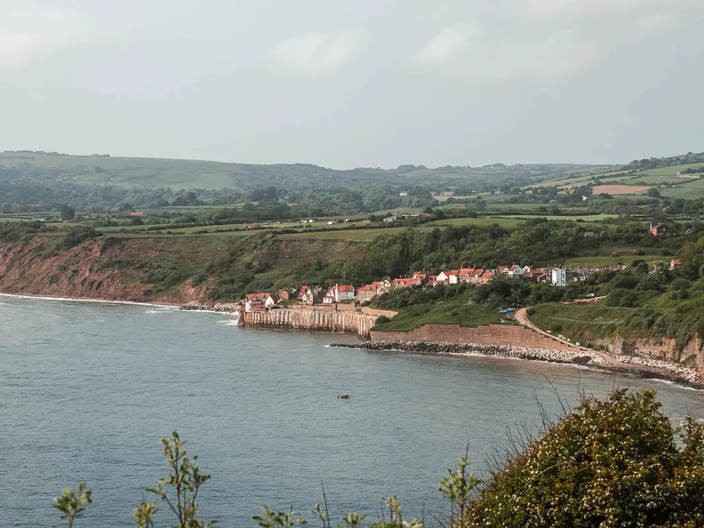 Looking across the North Sea, towards the cute little village of Robin Hood's Bay on the coast, on the walk to Whitby. Behind the village is fields of green as far as the eye can see.