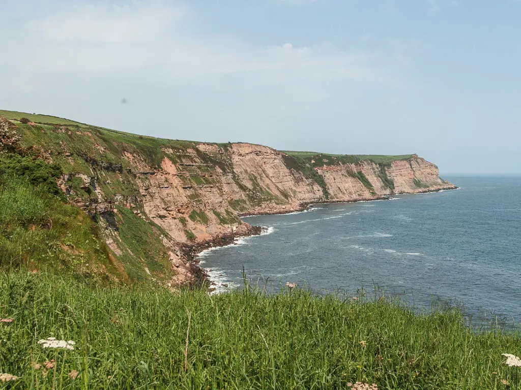 Looking over the grass, and along the cliff coastline, on the coastal walk to Whitby from Robin Hood's Bay. The 