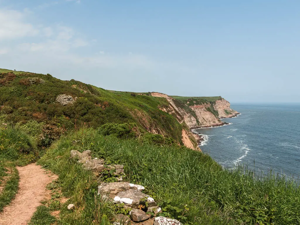 A dirt path on the left, with a strip of grass to the right, and the Ricky cliffs below, leading into the North Sea.