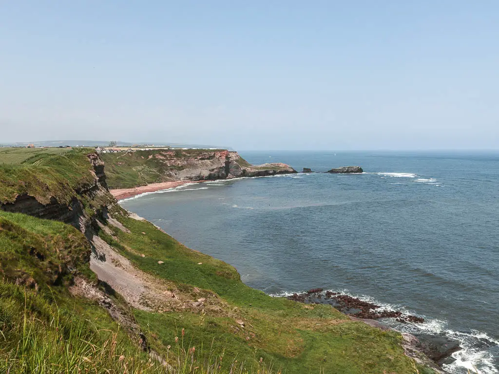 Looking along the curving coastline, with Saltwick Bay ahead, and the blue North Sea to the right, on the coastal walk between Whitby and Robin Hood's Bay.