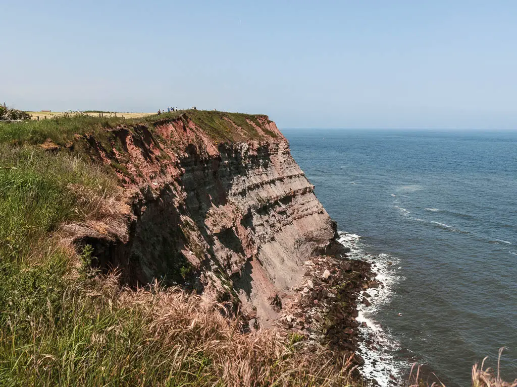 Looking down the rocky cliff face, with the sea below, near the end of the coastal walk from Robin Hood's Bay to Whitby. 