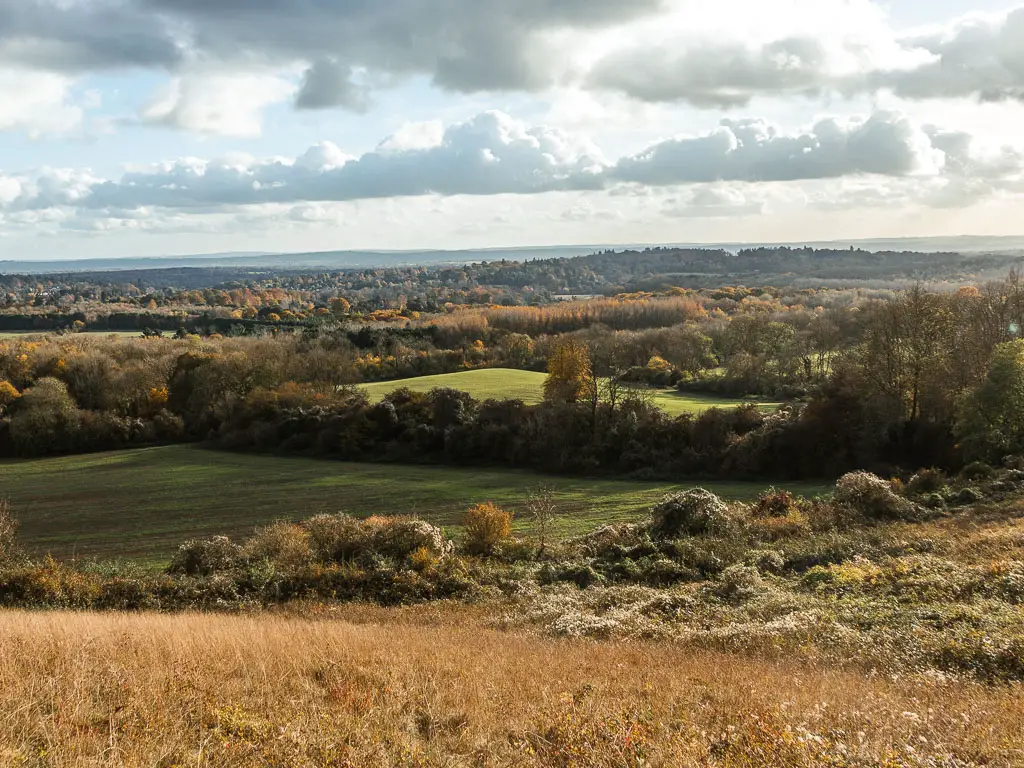 Looking down to a view of fields and trees as far as the eye can see, near the end of the walk between Merstham and Oxted.