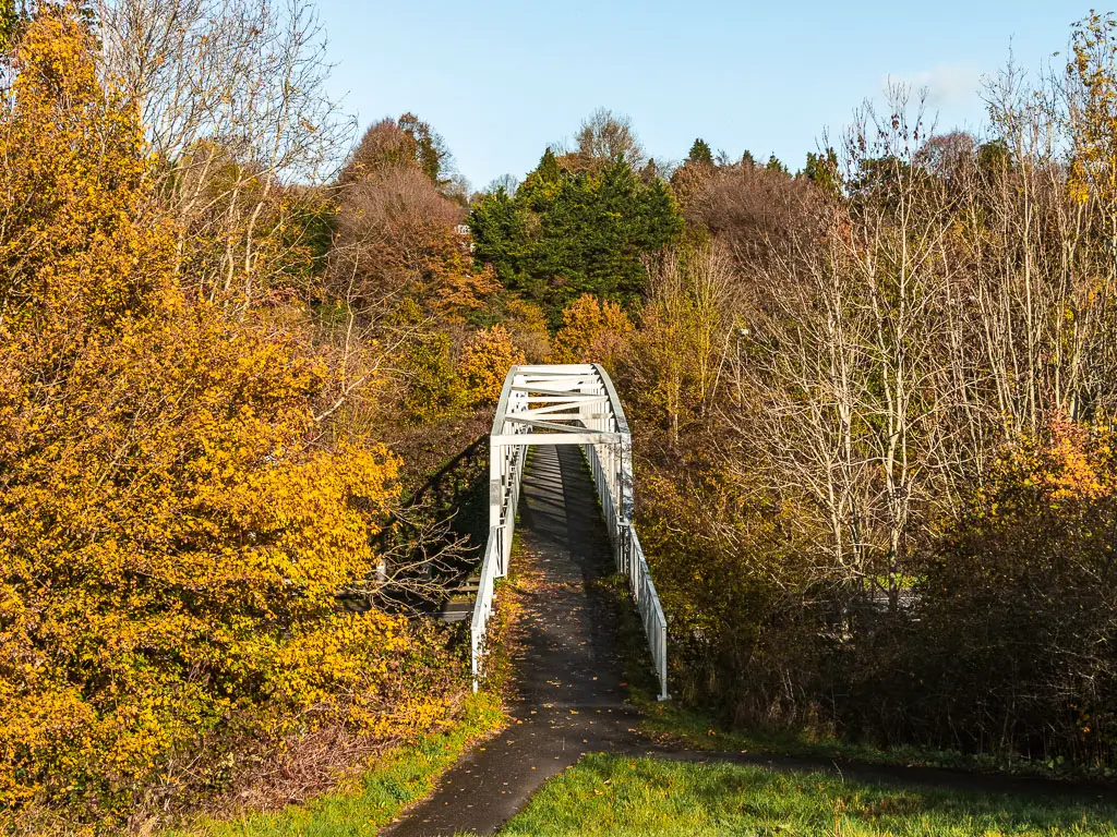 Looking down at a bridge with white railings, at the start of the walk from Merstham to Oxted. There bridge is surrounded by trees with yellow leaves.