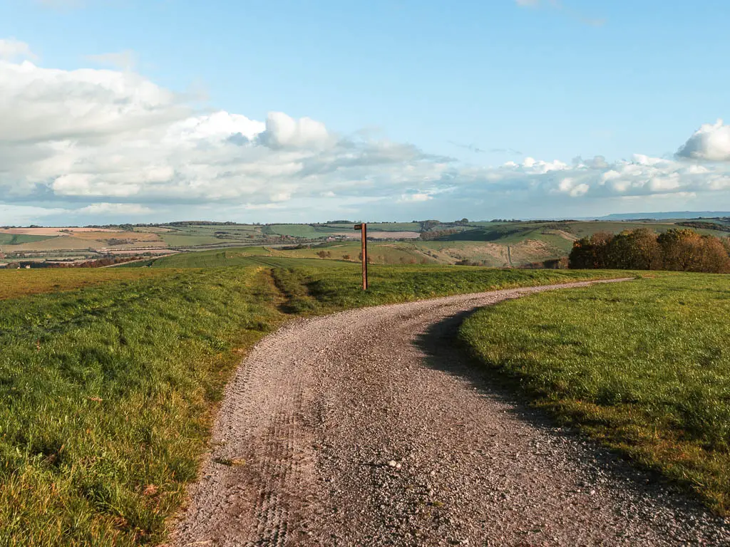 A gravel path curving to the right, with and expanse of fields straight ahead into the distance.