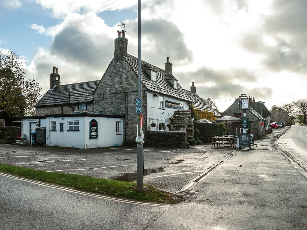 A white walled pub, with a road leading up to the left of it.