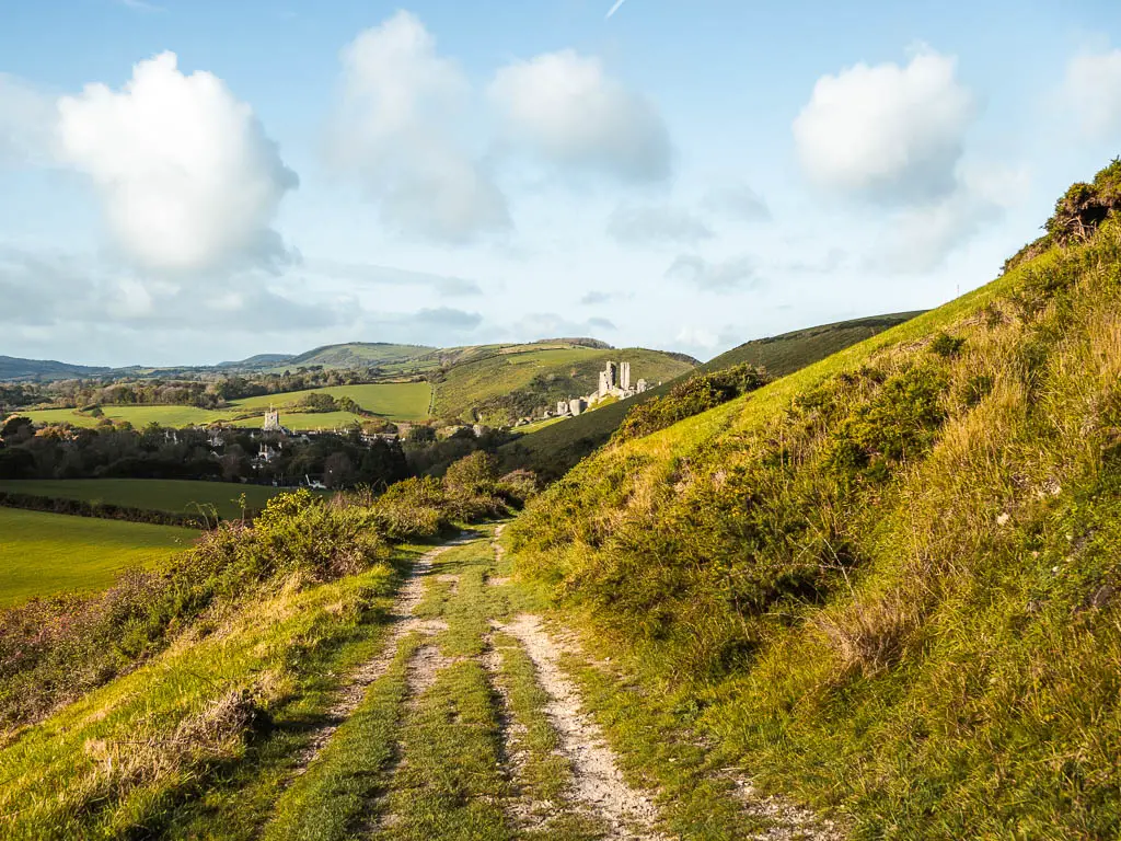 Looking down the trail on the hillside, with a view to Corfe Castle in the distance, on the walk towards Swanage. The castle is sitting in the dip between two hills.