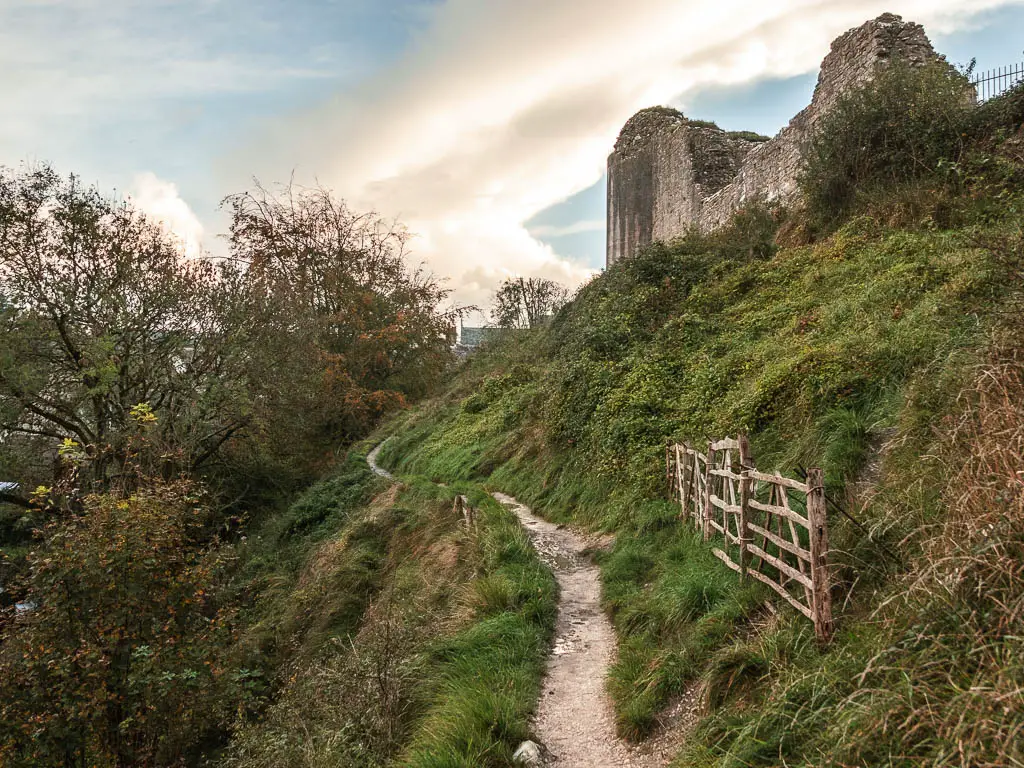 A narrow trail cutting across the side of the hill, with the ruins on Corfe Castle up the hill on the right.