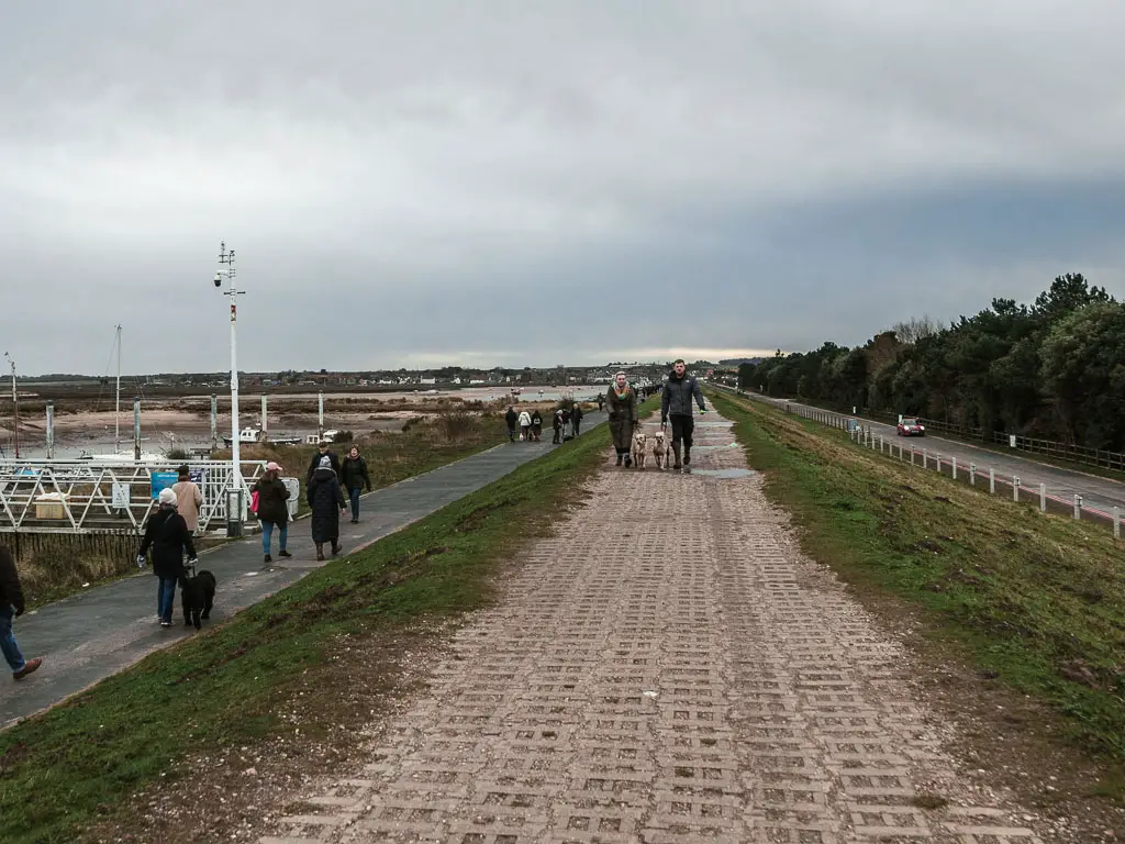 A ridge walkway with a walking path below to the left and road below to the right. There are lots of people walking about.