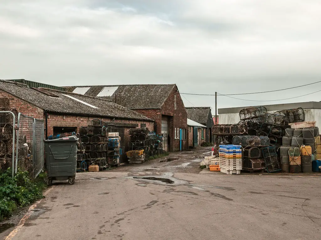 The road leading through and area filed with fishes baskets, and brick walled buildings to the left.