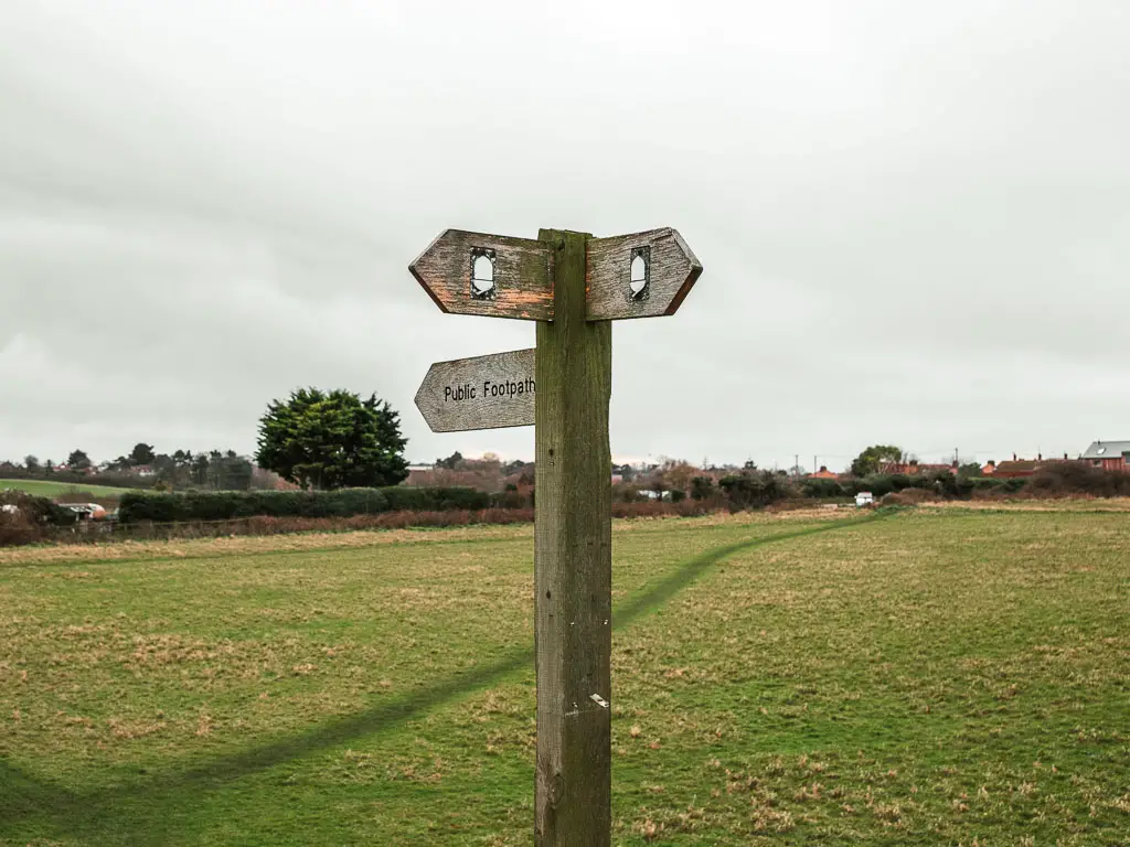 A wooden trail walking sign pointing left and back with a white acorn sign, on the walk between Burnham Overy Staithe and Blakeney.