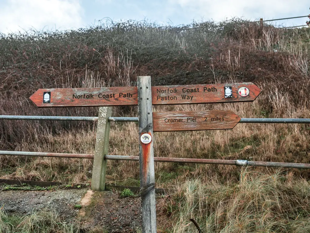 A wooden trail signpost pointing left and right for the Norfolk Coast path when walking between Cromer and Mundesley.