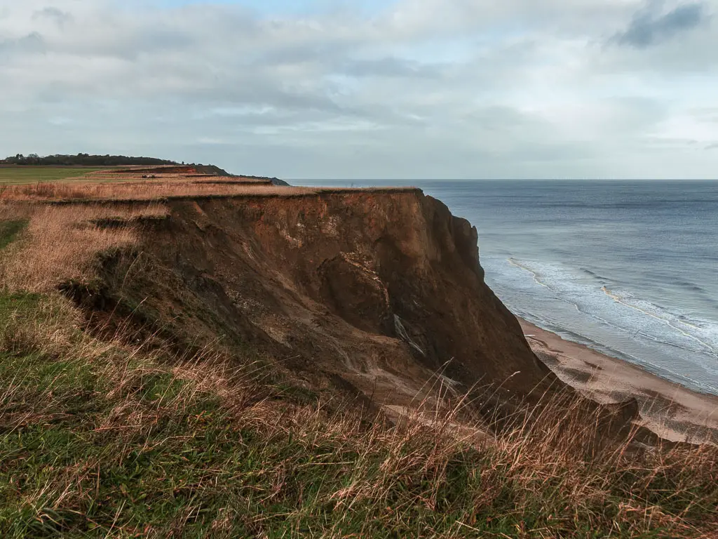 Looking down the rugged cliffside, as it drops down to the beach and sea below on the right, on the walk from Cromer to Mundesley.