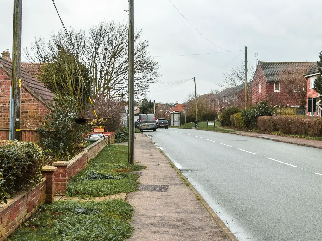 A residential road leading ahead, lined with brick walled houses. 