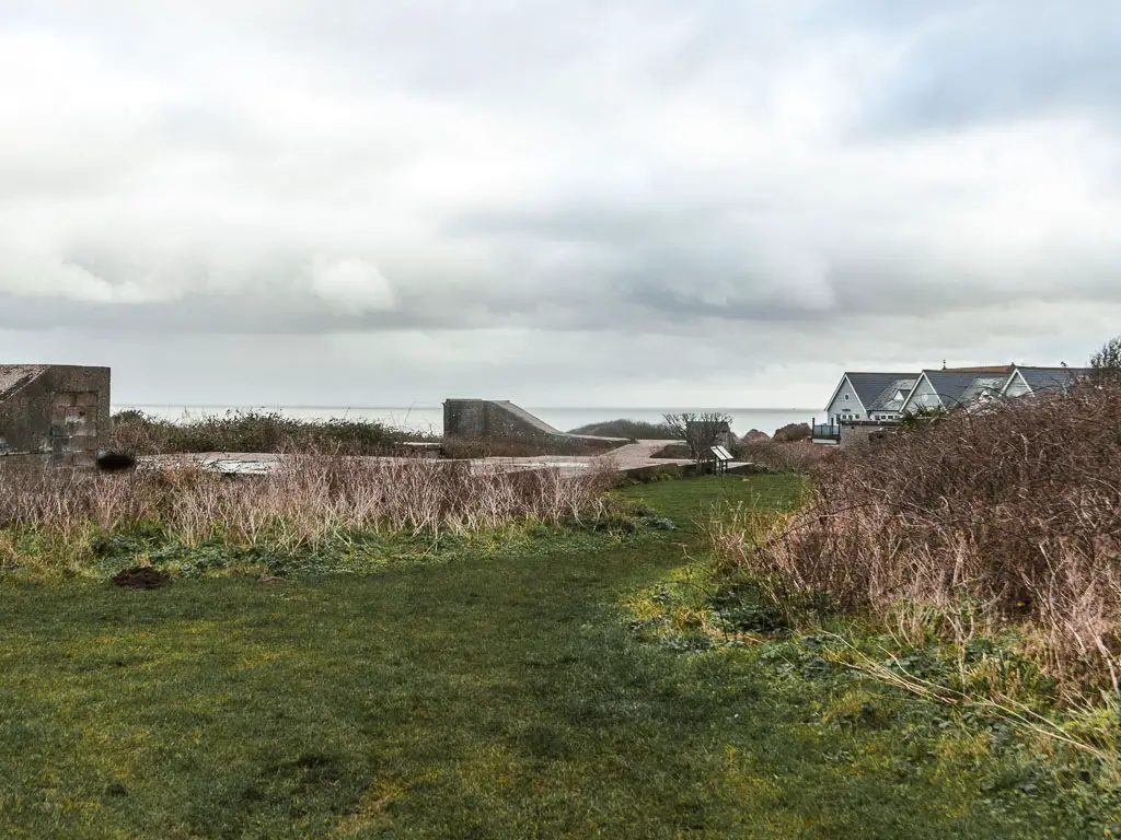 A grass area with the base of building ruins on the left.