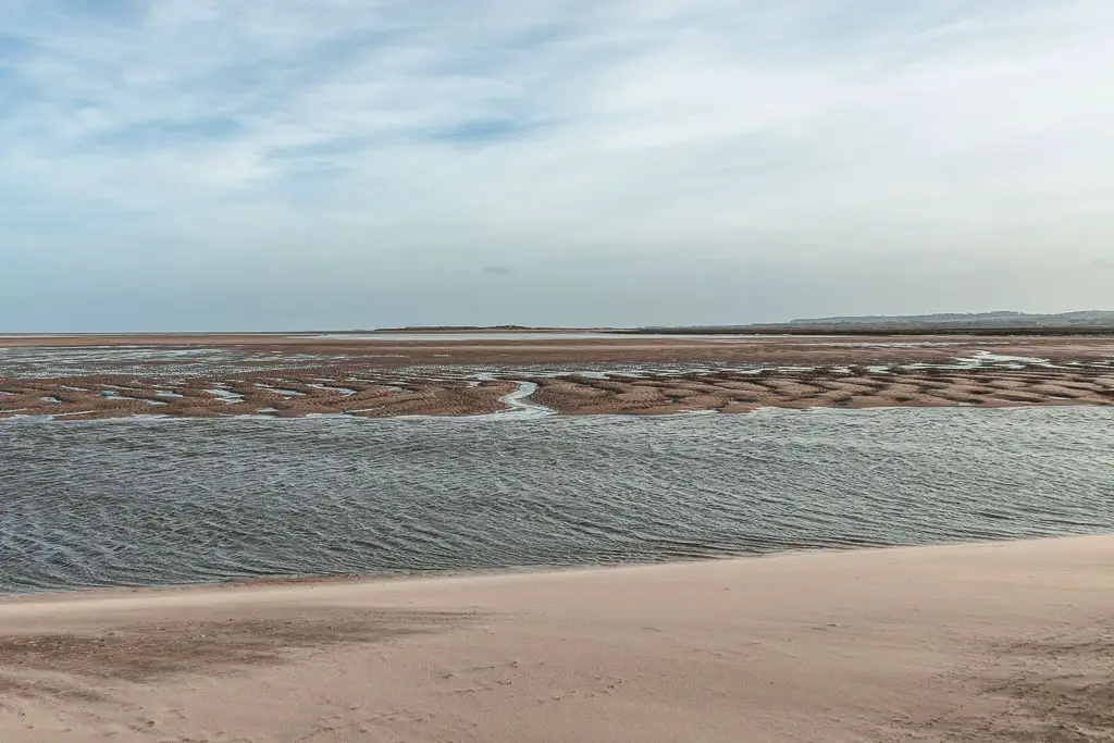 Where the sand beach meets a river running across the screen. 