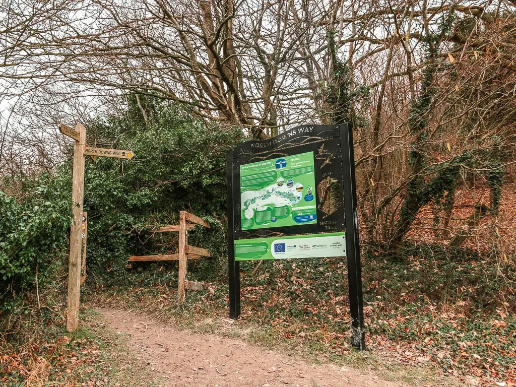 A black information board on the trail, with trees behind it.