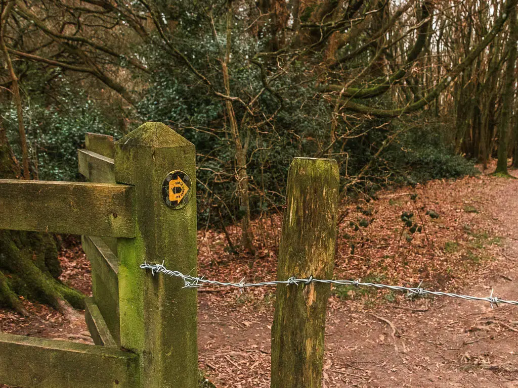 A wooden gate with a yellow arrow pointing right.