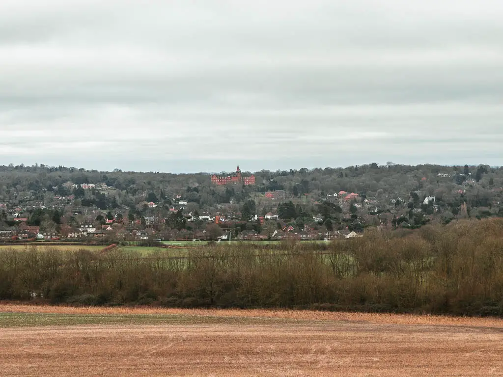 Looking across a large field to three tops and houses in the distance. 