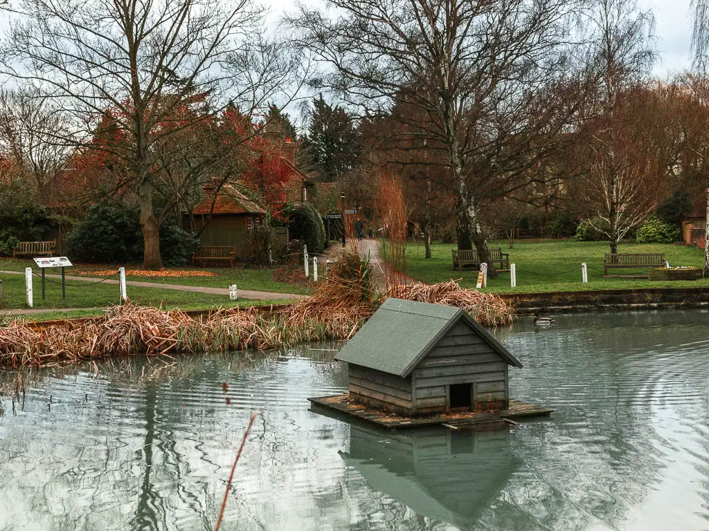 A pond with a duck house in the middle, at the end of the walk in Otford.