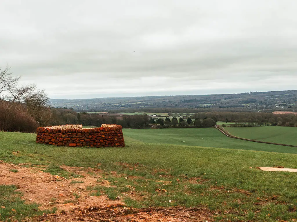 Looking across a large grass field, to a brick circular bunker type thing on the left. 