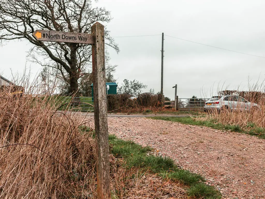 A wooden trail signpost on the left side of a gravel path.