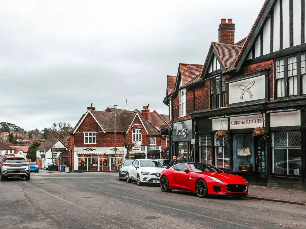 A street with shops on the right, snd park cars.