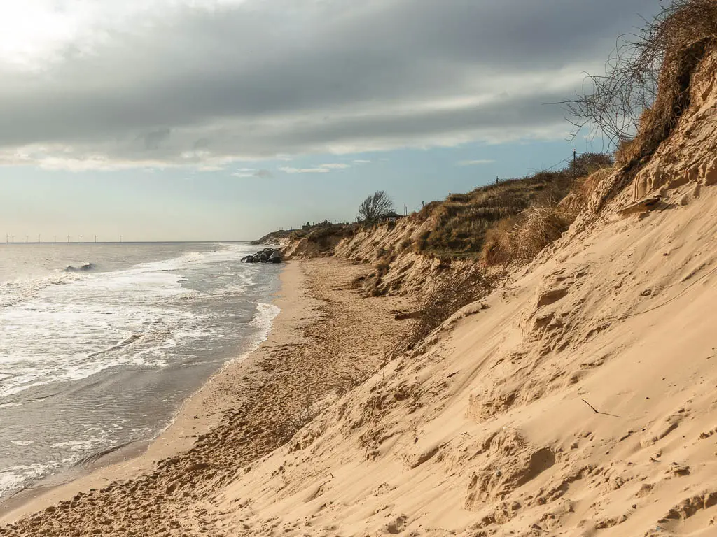 Looking down along the sand dune as it meets a small strip of beach below, with the North Sea to the left, at the start of the walk from Hemsby to Great Yarmouth.