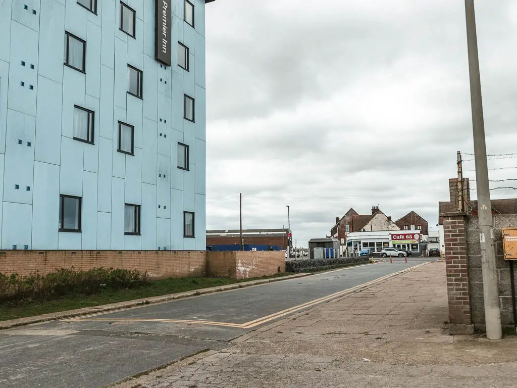 A road leading ahead, with a pale blue hotel building to the left.