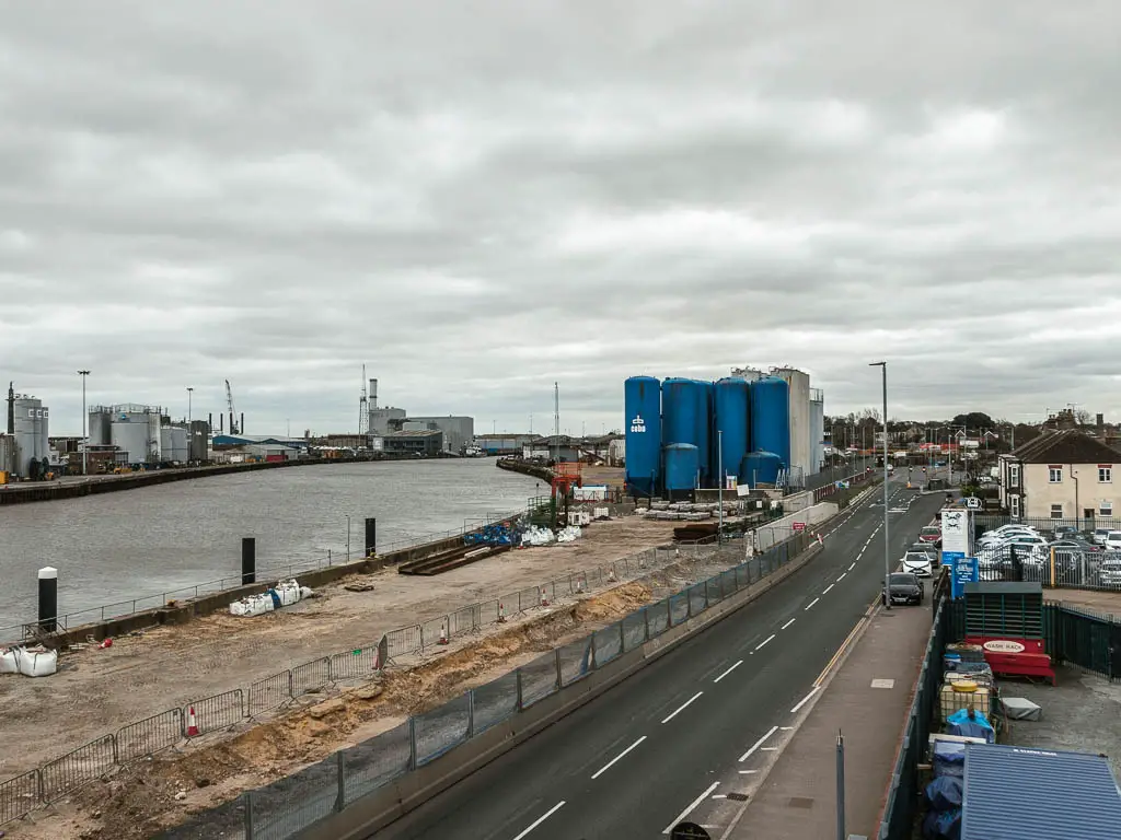 Looking down off the bridge to the road below with industrial structures and construction areas lining it.