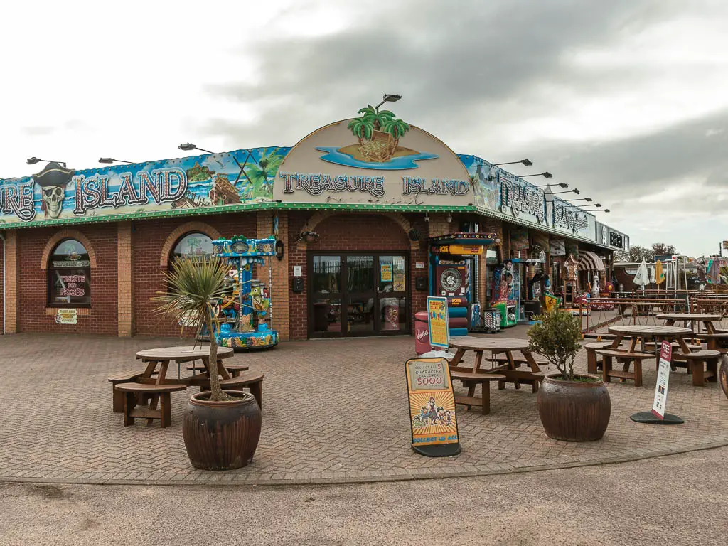 An arcade with picnic tables outside, on the road corner.