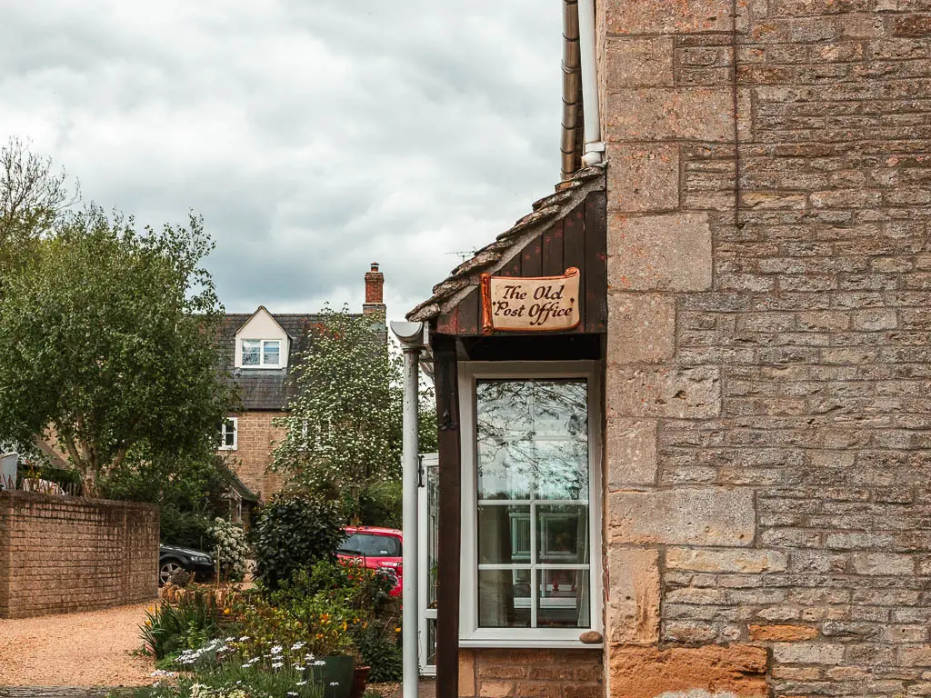 The side of a stone walled house with the old post office sign on it, on the walk from Cricklade to Lechlade.