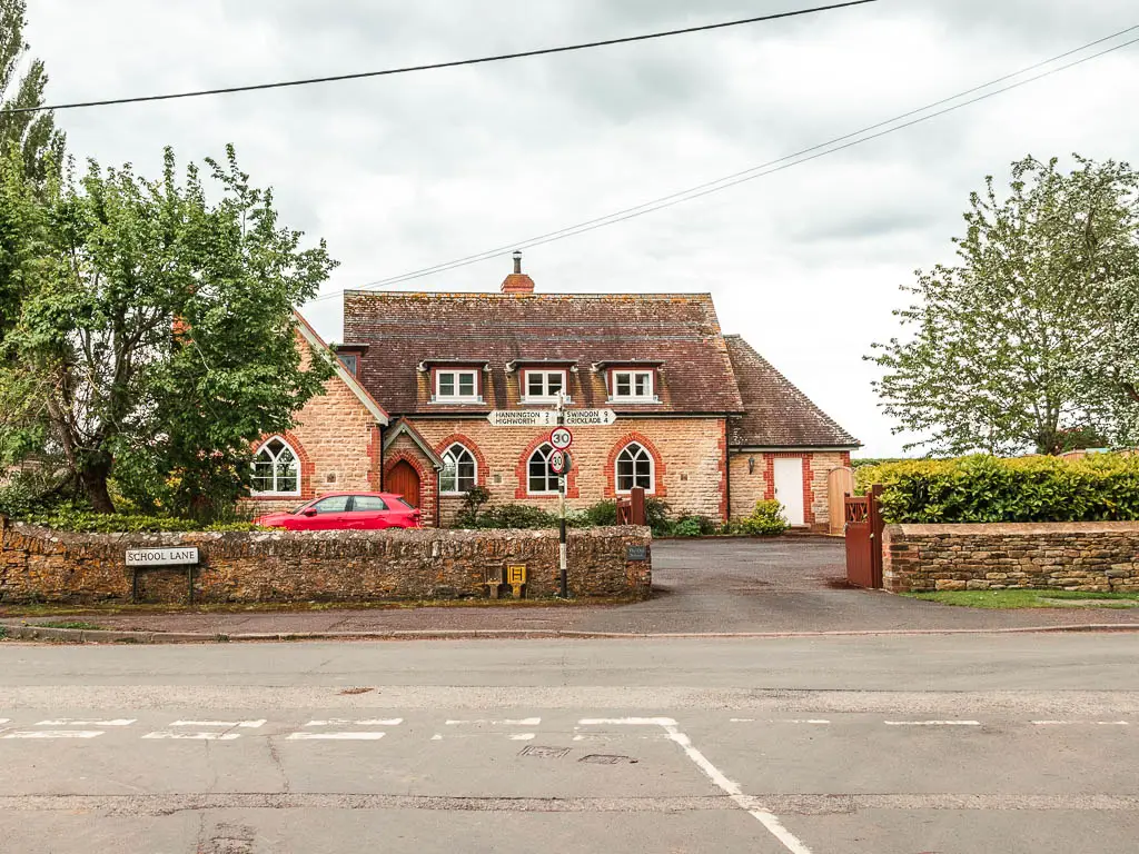 Looking across the road to a stone house and stone wall in front of it.