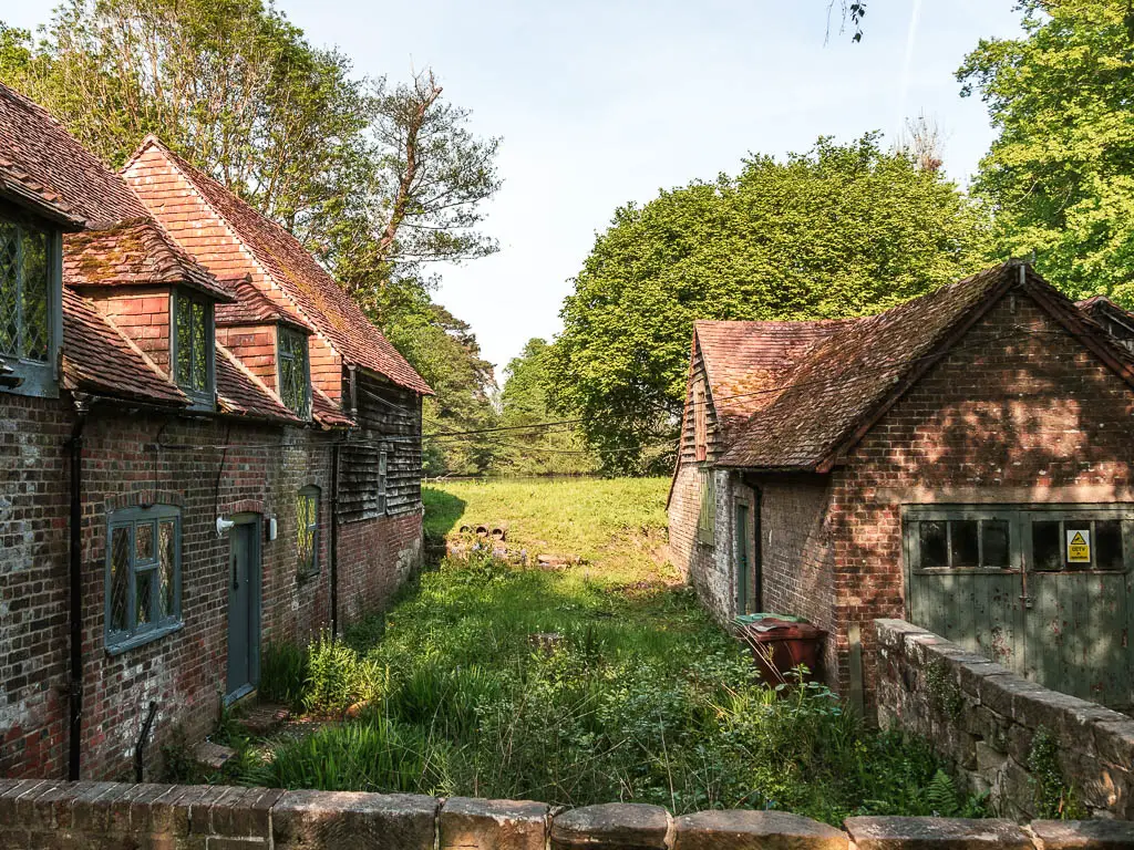 Looking down the strip of grass between two old brick buildings in Groombridge.