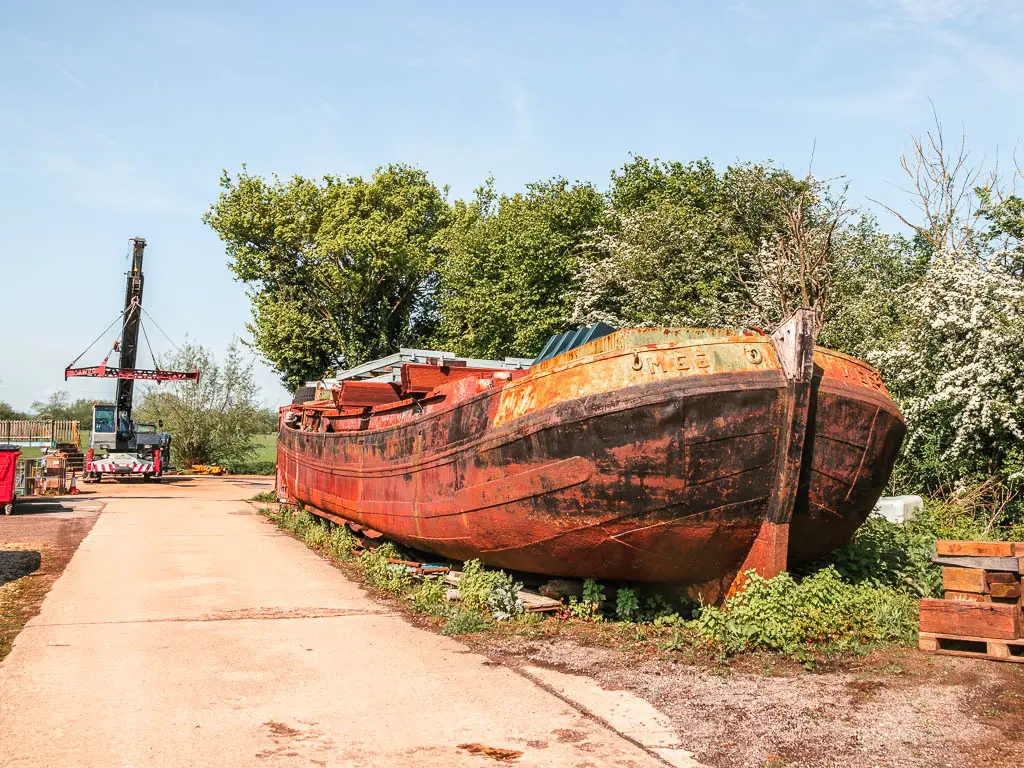 A big red rusty boat on the right side of the wide path.