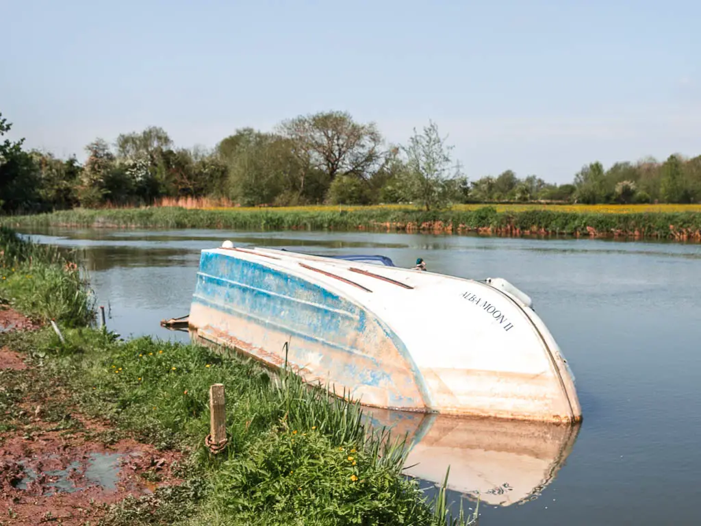 A white boat half sunken on it's side in the river, on the Newbridge to Oxford walk.