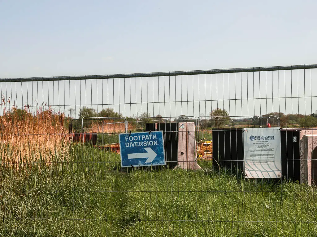 A metal fence with blue sign saying 'footpath diversion' and white arrow pointing right.