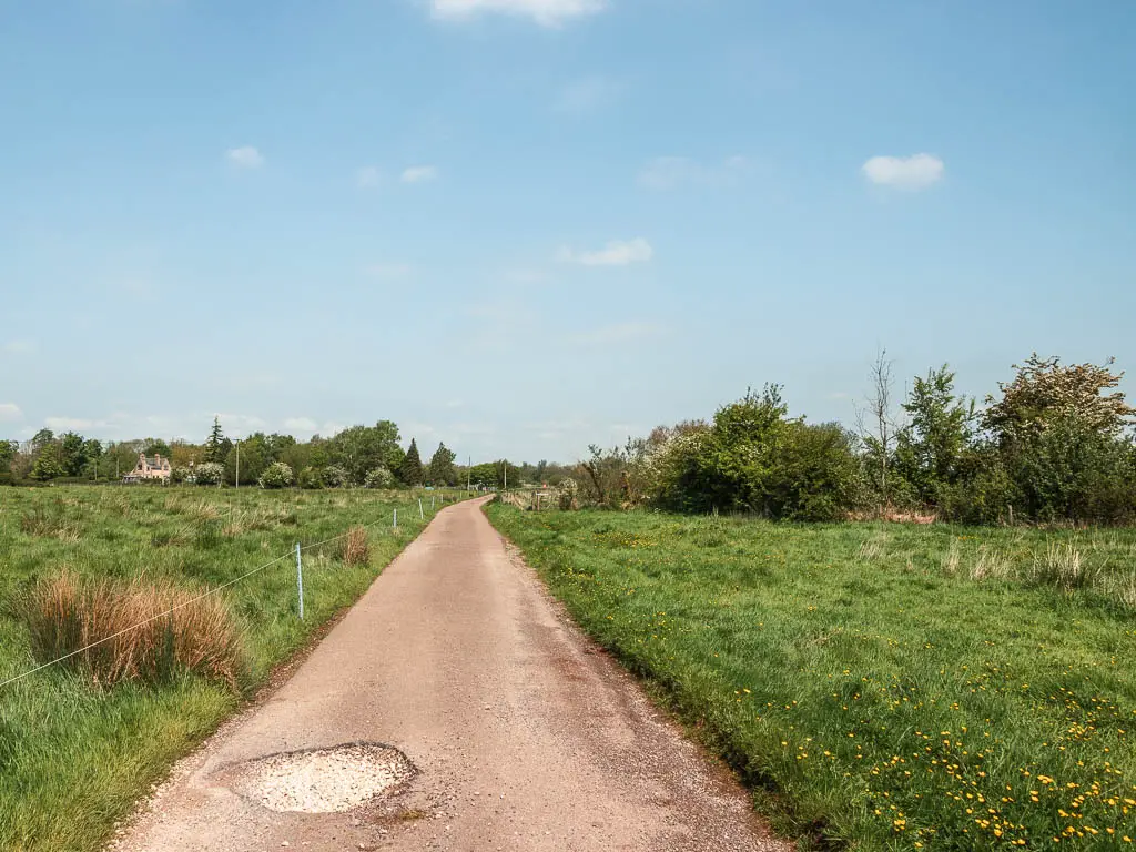 A long straight wide path leading ahead, lined with green grass.