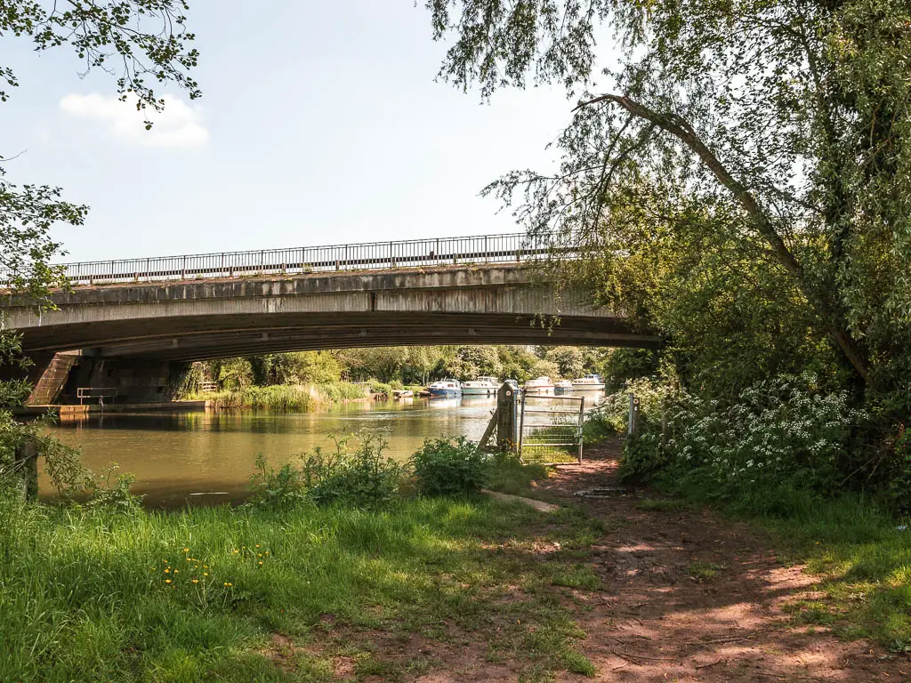 A dirt path leading towards a bridge over the river.