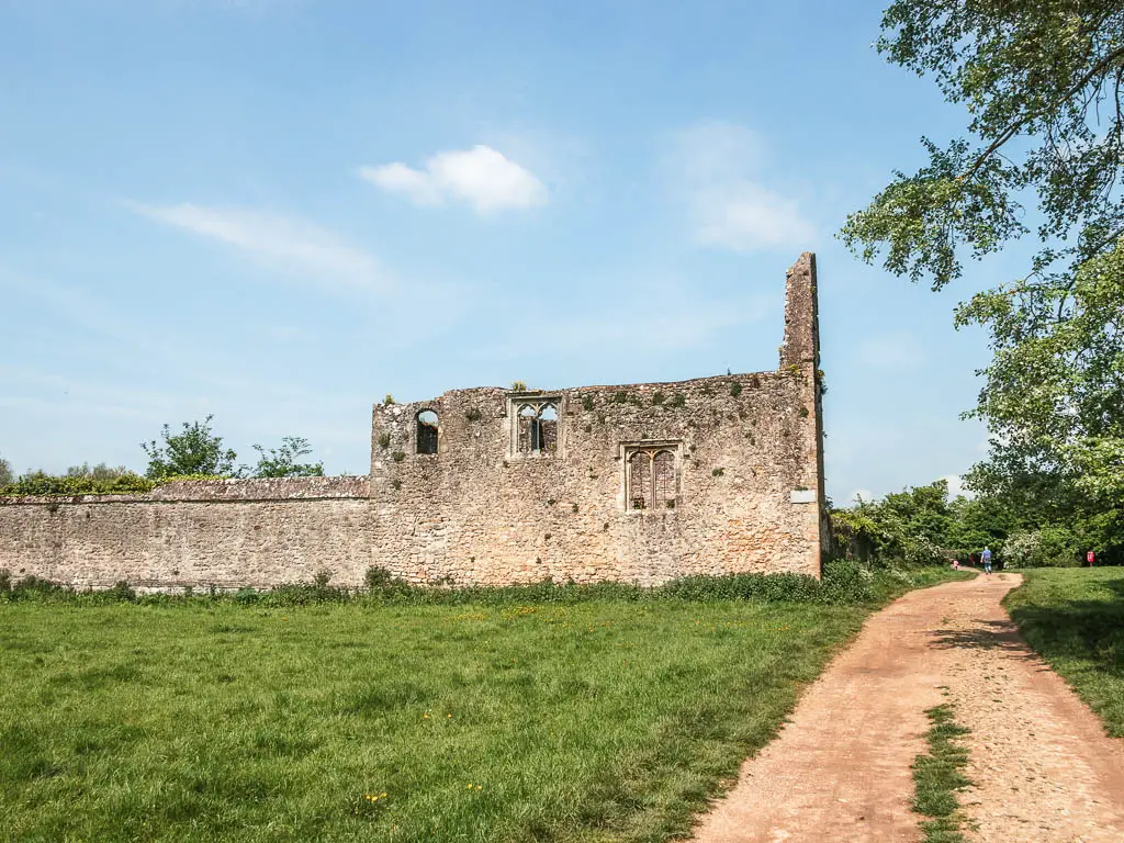 A path on the right and abbey ruins on the green on the left.