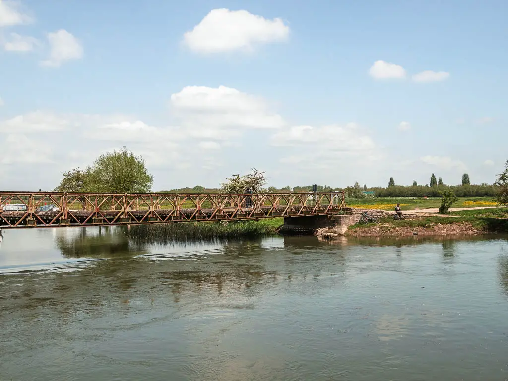 Looking across the river with a metal bridge on the left side.